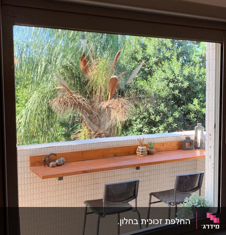 חלון זכוכית עם נוף של עצים ופריטים על מדף